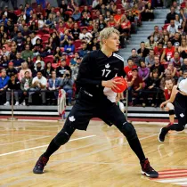Professional athlete playing a ball sport in front of a crowd in a gymnasium. 